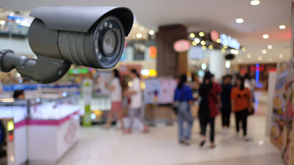 零售店内的视频监控摄像头，背景中是一群模糊的顾客